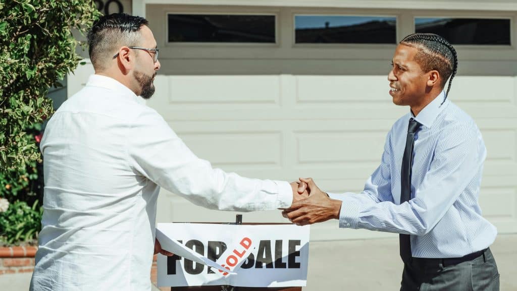 Home 43 Two men shaking hands, sold sign