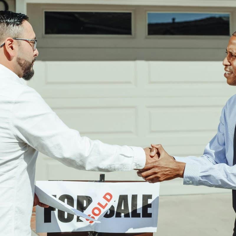 How to Sell a House With a Lien On It 3 Two men shaking hands, sold sign