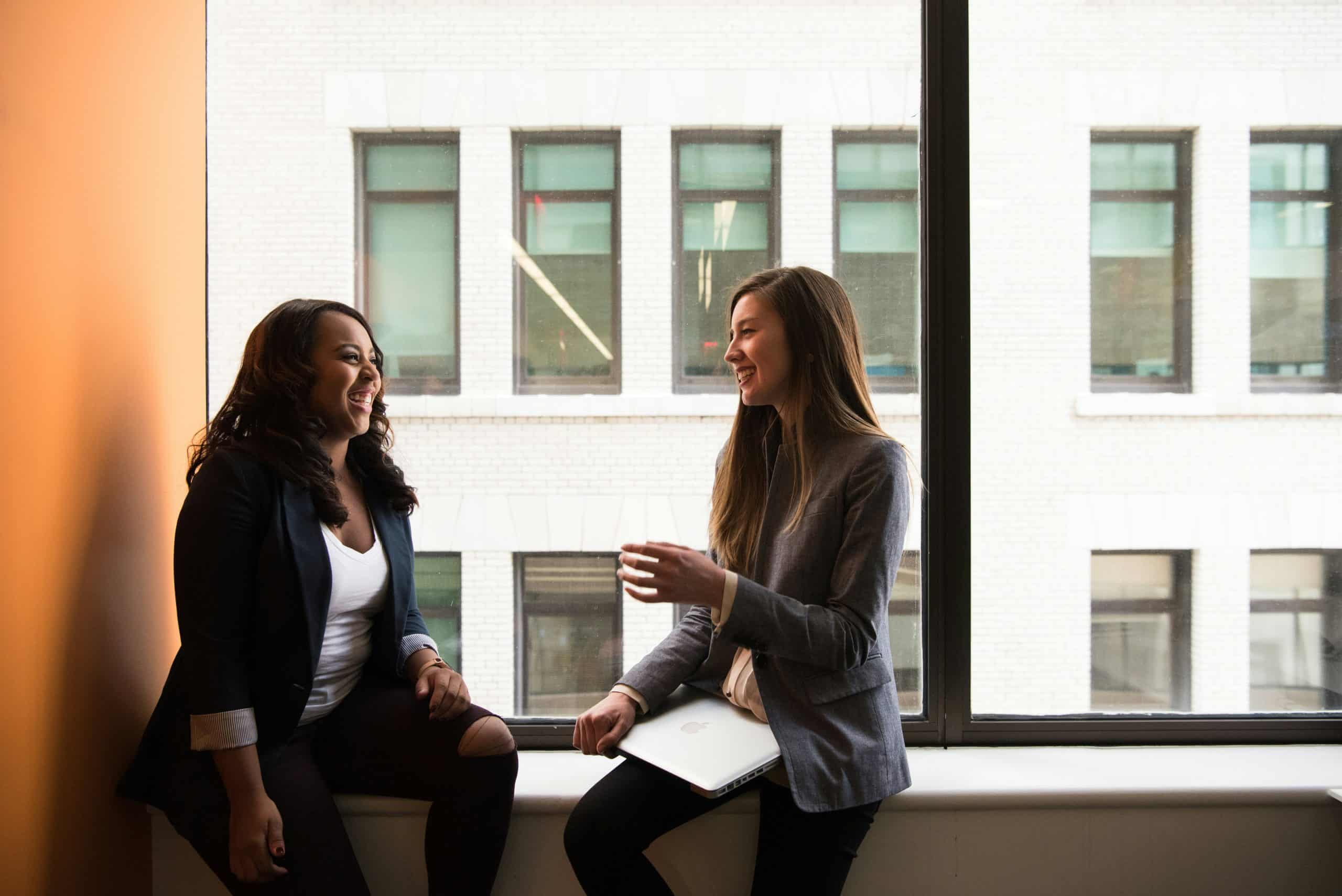 Two women chatting by a window